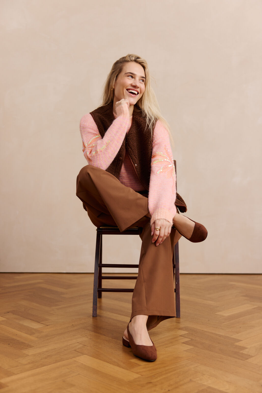 Model smiling wearing a orange pastel pullover